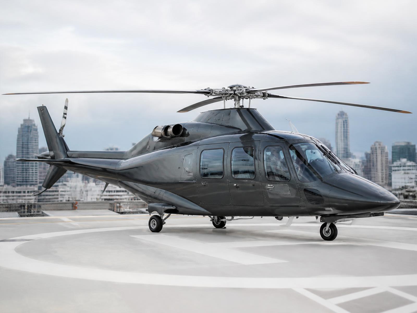 Executive helicopter on a city rooftop helipad at dusk