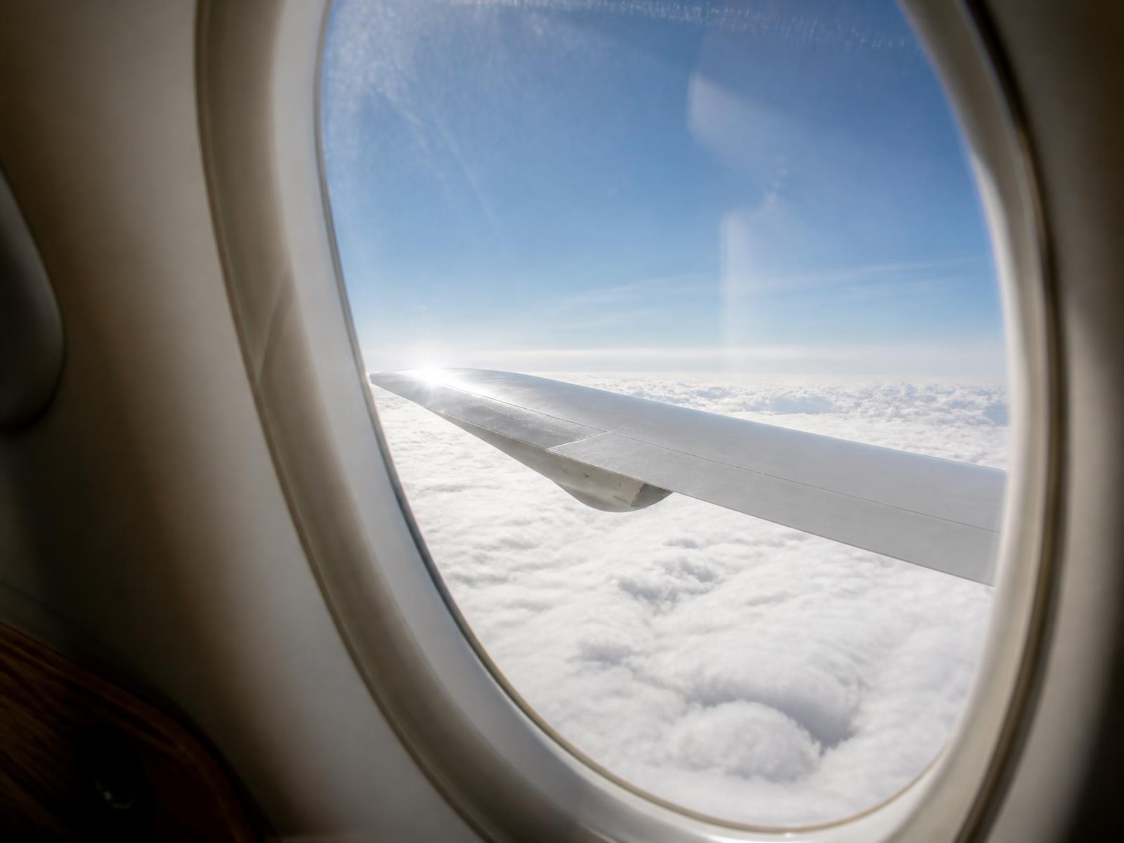 View of a jet wing above a sunset cloud layer from the cabin window